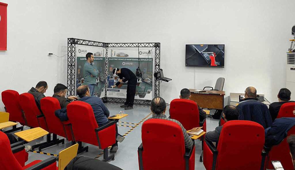 Simülatörü kullanan kişinin yaptığı hareketleri televizyondan eş zamanlı olarak izleyen Elektrikli araç eğitimi alan 20 kişilik sınıf.